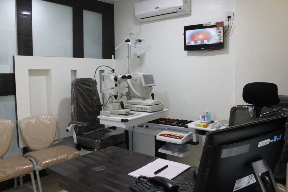 Ophthalmic consultation room at Insight Institute with binocular slit-lamp, doctor's desk, Snellen chart display and a wall-mounted patient education monitor